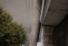 Atado con alambre: un vecino debió amarrar un poste a su casa para que el temporal no se lo llevara puesto. En la misma cuadra, la desidia quedó a la vista con otro poste desplomado sobre el asfalto.