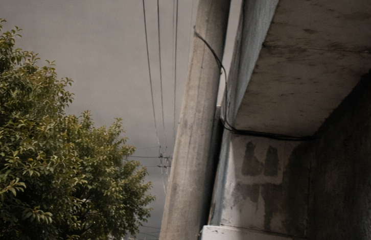 Atado con alambre: un vecino debió amarrar un poste a su casa para que el temporal no se lo llevara puesto. En la misma cuadra, la desidia quedó a la vista con otro poste desplomado sobre el asfalto.