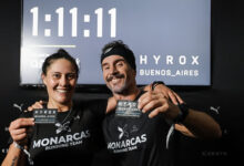 Yésica Herrera y José Pablo Leoni posan sonrientes junto al reloj oficial que inmortalizó su marca de 1:11:11 en el predio de La Rural. Foto: Hyrox Buenos Aires.