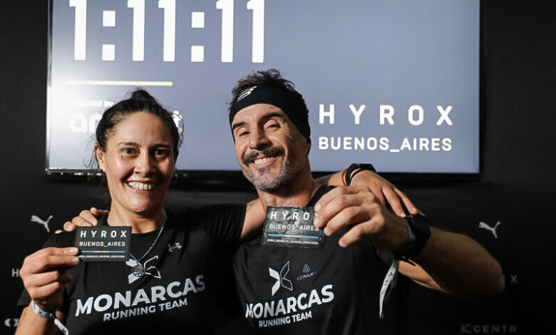 Yésica Herrera y José Pablo Leoni posan sonrientes junto al reloj oficial que inmortalizó su marca de 1:11:11 en el predio de La Rural. Foto: Hyrox Buenos Aires.